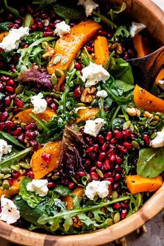 a salad with spinach, carrots, feta cheese and pomegranate