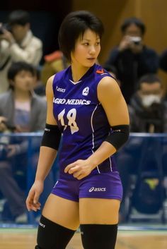 a female volleyball player in purple uniform standing on the court with her foot up and looking at the ball