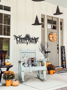 a porch decorated for halloween with pumpkins and decorations on the front door, including a bench