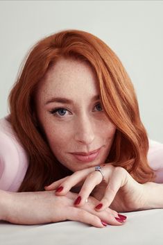 a woman with red hair laying on top of a bed