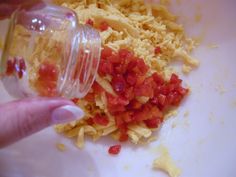 a person is pouring something into a bowl filled with rice and red peppercorst