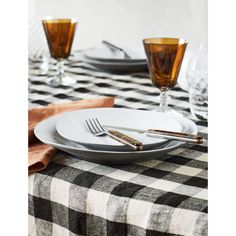 a black and white checkered table cloth with silverware on it, next to two glasses