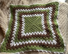 a crocheted square sitting on top of a blanket