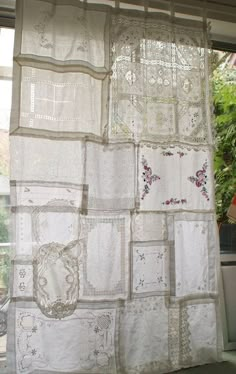 the curtains are covered in white linens and have embroidered designs on them, as well as flowers