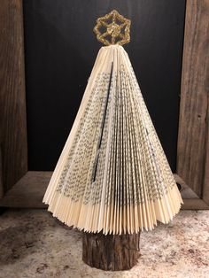 an origami christmas tree made out of old book pages with a gold star on top