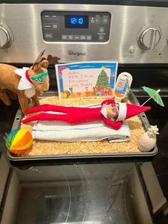 an elf laying on top of a stove next to a christmas card and other items