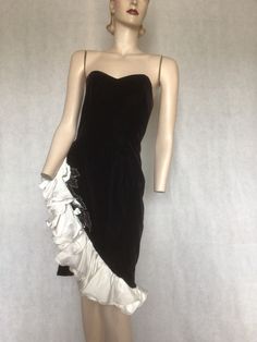 "Vtg 80s Black Velvet Cocktail, NYE Formal Party Dress with white ruffle Dave & Johnny S Preowned. Condition 8/10.  I marked this as so because there is faint reddish hues evident in daylight under the arms.  This is the colour underneath the black dye and occurs with contact with oil, perfume, etc.  at nighttime the reddish hue is not evident. Style A black velvet vixen rock chick evening dress.  Asymmetrical line with the hem lined with a white ruffle edged with memory wire, and a beaded sequinned edge piece adding stark contrast to the inky black velvet. The dress is fully lined  It fastens with a long rear centre zip. The bodice is boned at the side seams and the bra cups. Make an entrance and exit in this number Labelled 7/8 in USA sizing. The dress fits a 10 Australian  Go by measure Vintage Party Dress With Ruffle Hem, Retro Vintage Dress With Ruffles For Formal Occasions, White Vintage Dress With Ruffles For Evening, White Ruffled Vintage Evening Dress, Sleeveless Ruffled Vintage Dress For Evening, Formal Fitted Vintage Dress With Ruffles, Fitted Vintage Dress With Ruffles For Formal Occasions, Retro Vintage Evening Dress With Ruffles, Retro Vintage Dress With Ruffles For Evening