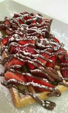 chocolate covered waffles with strawberries and powdered sugar on the top are ready to be eaten