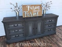 an old dresser is painted black and has flowers in vases on the top, along with a sign that says farm sweet farm