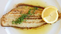 grilled fish with lemon and parsley on a white plate