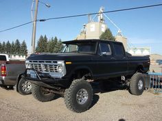 a large black truck parked next to a white truck