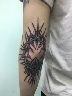 a man's arm with tattoos on it that has spikes in the middle and is black