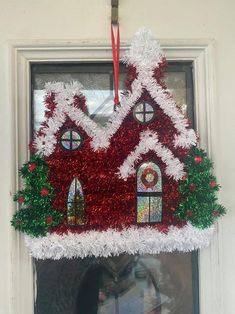 a christmas decoration hanging on the side of a door with a window in the background