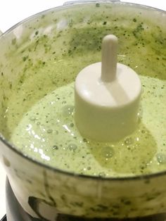 a food processor filled with green liquid on top of a stove