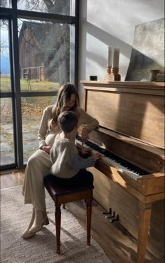 a woman sitting at a piano with a child