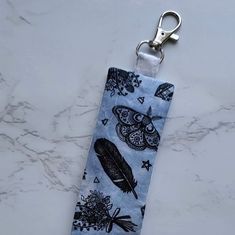 a keychain with an owl and feathers design on it sitting on a marble surface