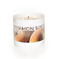 a white candle with cinnamon sugar doughnuts on the front and bottom in it