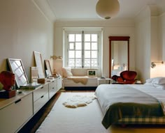 a bed room with a neatly made bed next to a dresser and a mirror on the wall