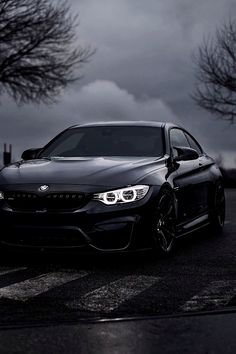 a black car is parked on the side of the road with dark clouds in the background