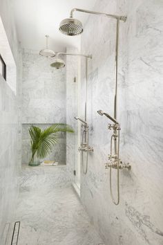 a bathroom with marble walls and flooring, shower head, and hand held showerhead