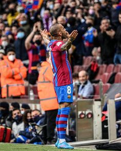 a man standing on top of a soccer field holding his hands up in the air