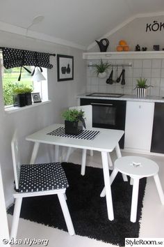 a white table and chairs in a small room with black and white rugs on the floor