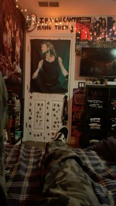 a bedroom with posters on the wall and plaid bedding in front of an unmade bed