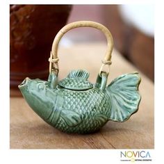 a teapot shaped like a fish sitting on top of a wooden table