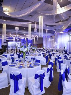 the banquet hall is decorated with blue and white linens, sashes, and centerpieces