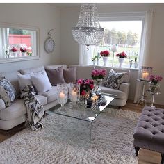 a living room filled with lots of furniture and flowers on top of a white rug