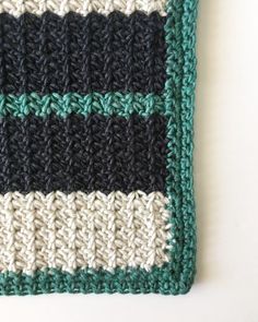 a crocheted dishcloth with black, white and green stripes