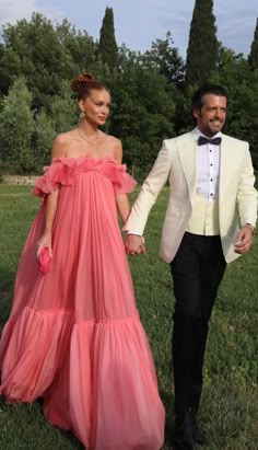 a man in a tuxedo and a woman in a pink dress holding hands