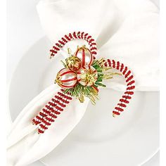 a white plate topped with a napkin covered in red and gold beaded decorations on top of it