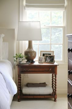 a bedroom with a bed, dresser and lamp in it's centerpiece next to a window