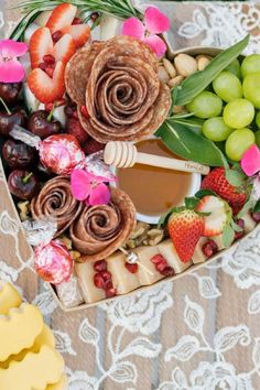 a heart shaped box filled with assorted fruit and cheeses on top of a lace tablecloth