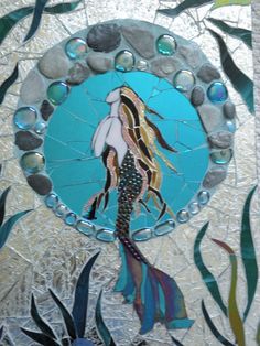 a stained glass window with an image of a mermaid in the water surrounded by seaweed