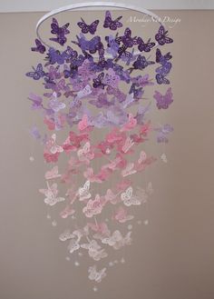 some pink and purple butterflies are hanging from a chandelier in a bedroom or playroom