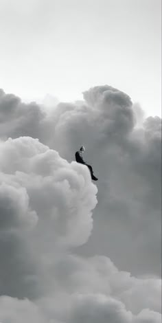 a man flying through the air on top of a cloud filled sky next to a jet