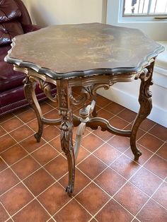 a table that is on the floor in front of a couch and window with a leather chair behind it