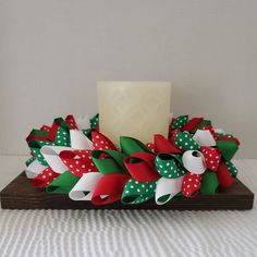 a candle sitting on top of a wooden table next to some christmas wreaths and bows