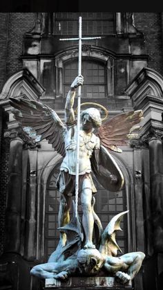 an angel statue on top of a building next to a cross and other statues in front of it