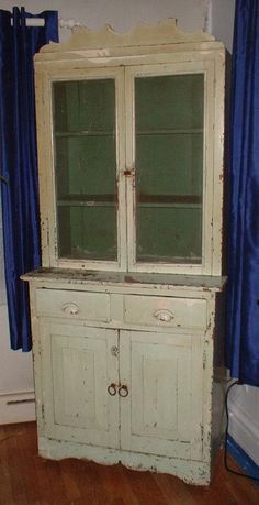 an old white china cabinet with glass doors