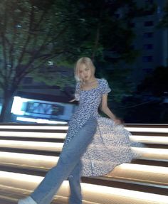 a woman is walking down some steps in the dark with her hand on her hip