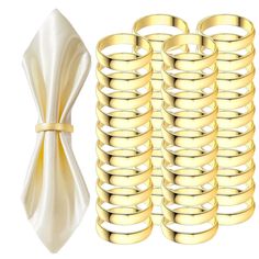 a bunch of gold colored rings next to a white vase with a bow on it