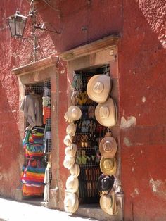 hats are hanging on the side of a red building with a light fixture above it