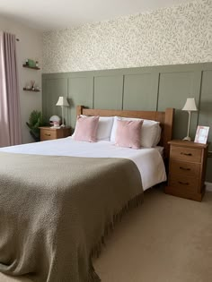 there is a large bed with pink pillows and blankets on the headboard in this bedroom