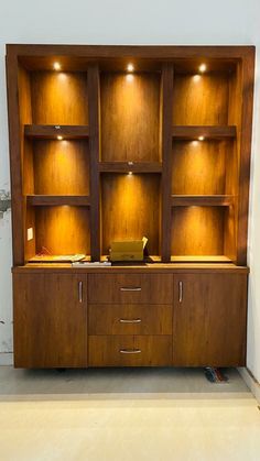 a wooden bookcase with lights on the top and bottom shelves in front of it