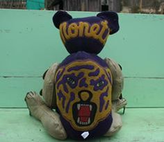 a stuffed animal with the word detroit painted on it's face sitting on a bench