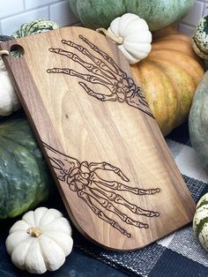 a wooden cutting board sitting on top of a table next to pumpkins and gourds