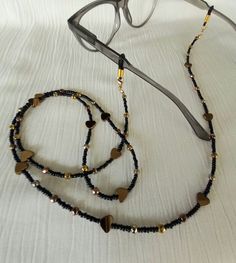 Sunglasses chain Eyeglasses chain Glasses chain This beautiful chain for glasses is made of small glass beads 2 mm in black, combined with hematite beads 4 mm in bronze and gold   shades. Hematite bronze hearts are 6-7 mm in diameter. At the end of the chain are gold plated buckles on which are silicone rubber glasses holders. If you remove the silicone rubber bands, the chain can also be a mask holder. The chain is effective and modern, it can be a very nice Christmas gift. If you buy this chai Black Adjustable Glasses Chain For Parties, Elegant Black Glasses Chains For Party, Beaded Metal Glasses Chains For Party, Metal Beaded Glasses Chains For Party, Metal Glasses Chain With Adjustable Chain As Gift, Metal Glasses Chains As Gift, Black Metal Glasses Chain With Adjustable Feature, Black Metal Glasses Chains With Adjustable Chain, Black Metal Glasses Chain With Adjustable Length